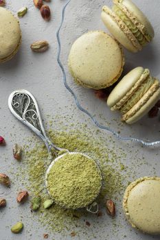 Pistachio flour and green macaroons on a gray background
