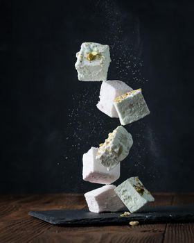 Flying dessret - nut marshmallow cubes on a dark background