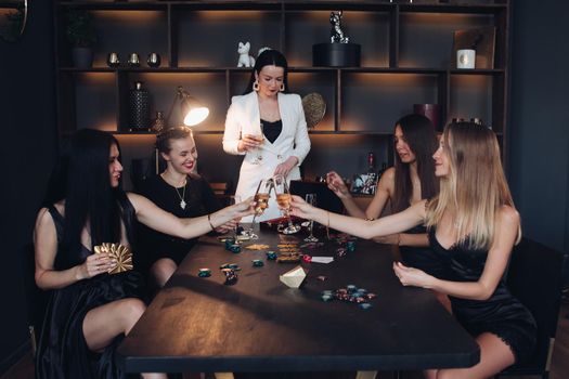 Group of fashion young sexy woman enjoying playing poker and drinking champagne medium long shot. Few glamour rich luxury female relaxing at casino drink alcohol beverage having party