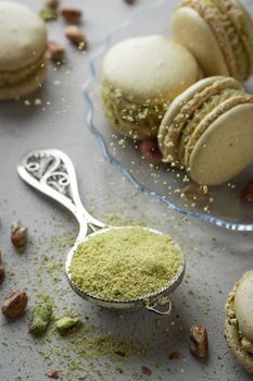 Pistachio flour and green macaroons on a gray background