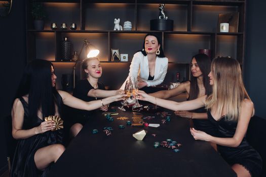 Group of fashion young sexy woman enjoying playing poker and drinking champagne medium long shot. Few glamour rich luxury female relaxing at casino drink alcohol beverage having party