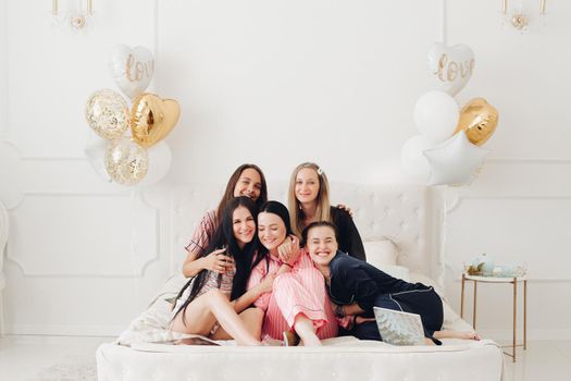 Smiling beautiful women in sleepwear spending time together during home party. Birthday party concept