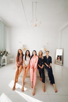 Smiling beautiful women in sleepwear spending time together during home party. Birthday party concept