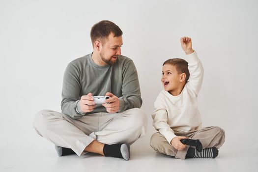 Paternity. Father and son play gamepad console game laugh and have fun together. Gamers play computer games