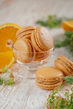 Macaroons with orange and caramel on a wooden table