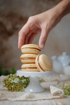 Stack of caramel macaroons on a stand on a wooden background