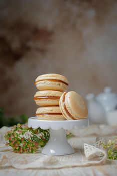 Stack of caramel macaroons on a stand on a wooden background