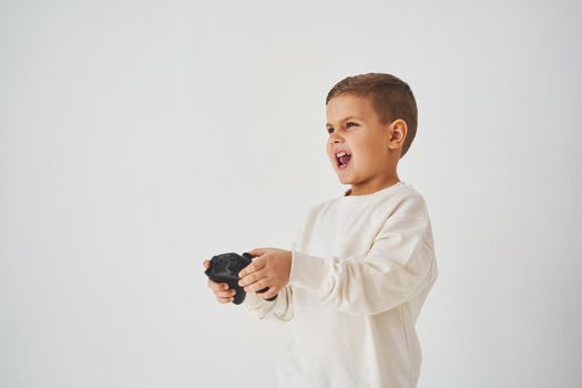 Expressive boy gamer plays computer games with a gamepad. Children's gambling.
