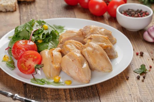 Roasted quail breasts with vegetables on a wooden table