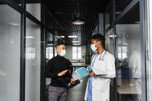 Asian patient with x-rays asks an African doctor about treatment of pneumonia and pleurisy. Black surgeon consult and help Asian man