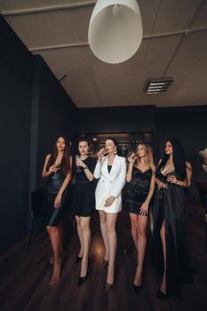 Group of fashion young sexy woman enjoying playing poker and drinking champagne medium long shot. Few glamour rich luxury female relaxing at casino drink alcohol beverage having party