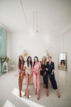 Smiling beautiful women in sleepwear spending time together during home party. Birthday party concept