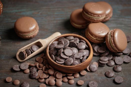 Macaroons with a chocolate drops on a wooden background