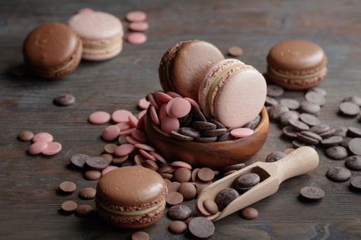 Macaroons with a chocolate drops on a wooden background
