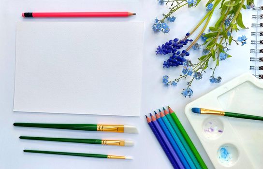 Flat lay sketchbook and pink violet, blue, purple and green pencils on white background. Artistic table top view photo