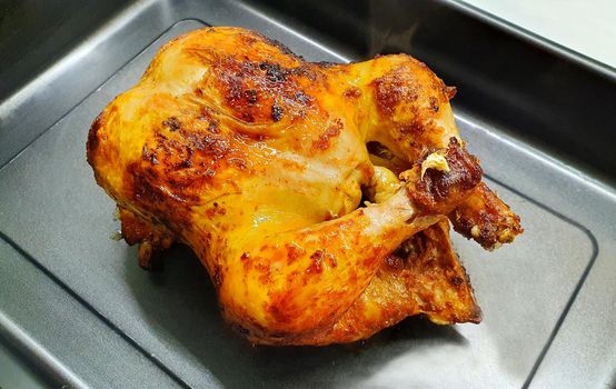 Closeup of whole juicy roasted chicken in the pan.