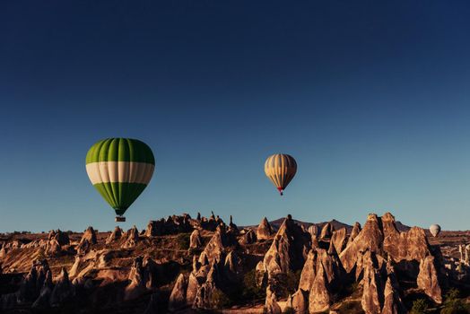 Hot air balloon flying over rock landscape at Cappadocia Turkey. Valley, ravine, hills, located between the volcanic mountains in Goreme National Park.