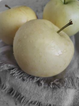 Ripe apples and red plums lie on a linen napkin on the table. Front view, close-up.