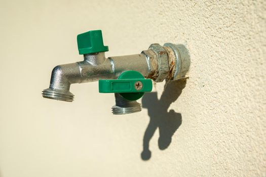 A double brass garden faucet mounted in the bright wall