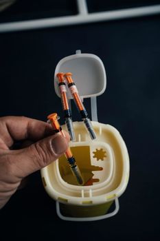 A person throwing a syringe into a medical waste container. medicine concept