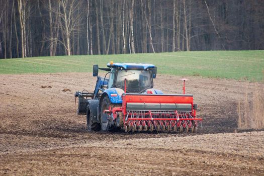 Tractor with a grain seeder in the field, spring view