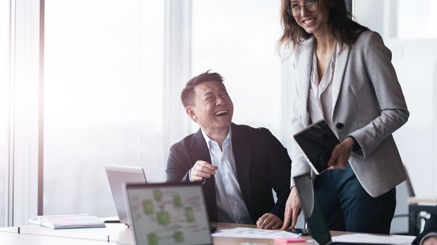 Business people in meeting room discuss project. Smiling portrait of diverse colleagues with tablet