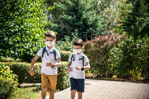 Happy schoolchildren with face masks run from the joy of returning to school during the Covid-19 quarantine.