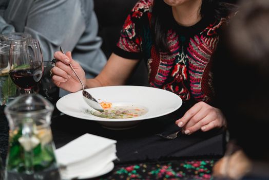 Woman eating mushroom cream soup in a restaurant.