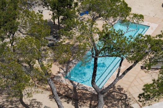 View through the trees to the swimming pool of a hotel on summer day. Vacation on summer resort.