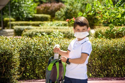 School child with backpack, face mask and sanitizer. Student safety after coronavirus pandemic. Virus and disease prevention for kids. Back to school and kindergarten after covid-19 outbreak.