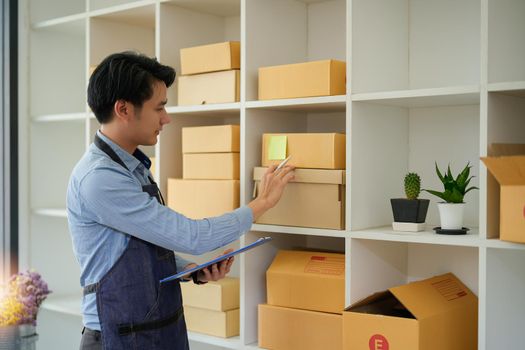 Young attractive asian owner startup business look at camera work happy with box at home prepare parcel delivery in sme supply chain, procurement, omnichannel or coronavirus quarantine concept.