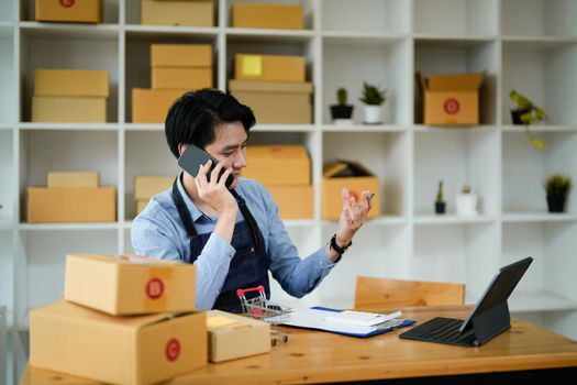 Portrait asian man are receiving orders via cell phone. Small business entrepreneur SME working with box at home, SME e-commerce digital technology concept