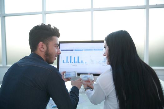 rear view.business couple discussing financial charts, sitting at your Desk.people and technology