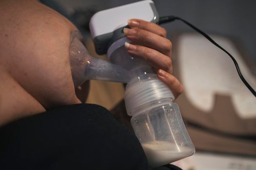 Young mother using an electric breast pump pumping breast milk for her baby.
