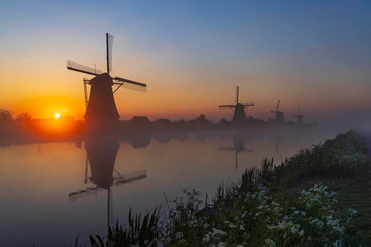 Traditional Dutch windmills with a colourful sky just before sunrise in Kinderdijk, The Netherlands