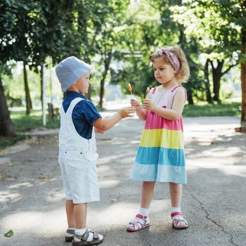 Happy children taste candy on a stick.