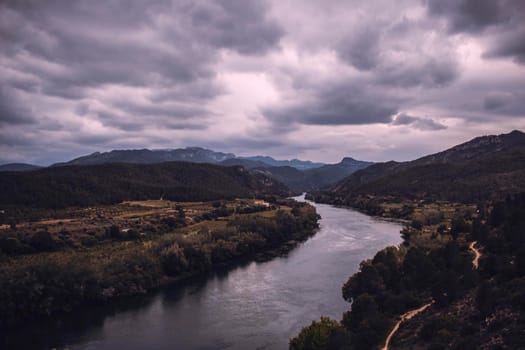 Curved river under a cloudy sky in Miravet town in Catalonia