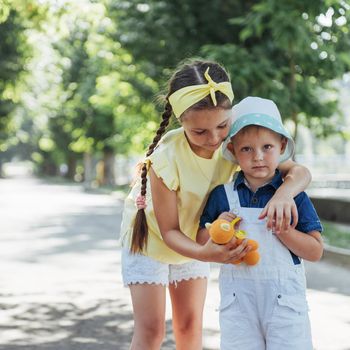 portrait of a little girl and her brother. Children playing outdoors on a sunny summer day. Family holidays.