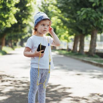 Cute girl listening to music with headphones outdoors.