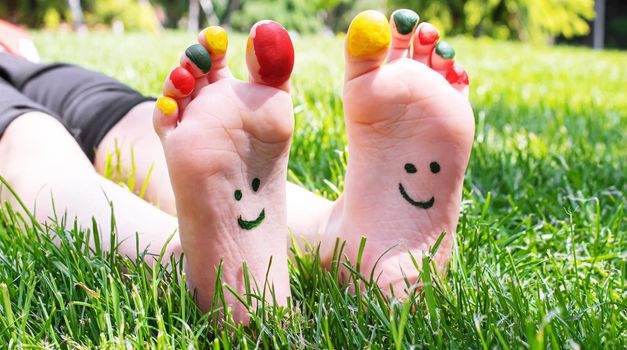 Children's feet with a pattern of paints smile on the green grass. Selective focus. nature.