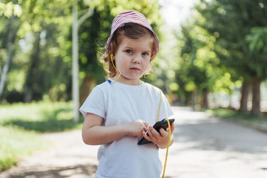 Cute girl listening to music with headphones outdoors.