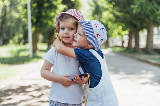 portrait of a little girl and her brother. Children playing outdoors on a sunny summer day. Family holidays.