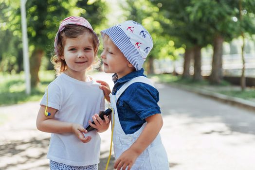 portrait of a little girl and her brother. Children playing outdoors on a sunny summer day. Family holidays.