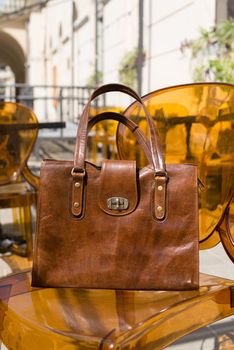 close-up photo of yellow leather bag on a stylish plastic chair. Outdoor photo