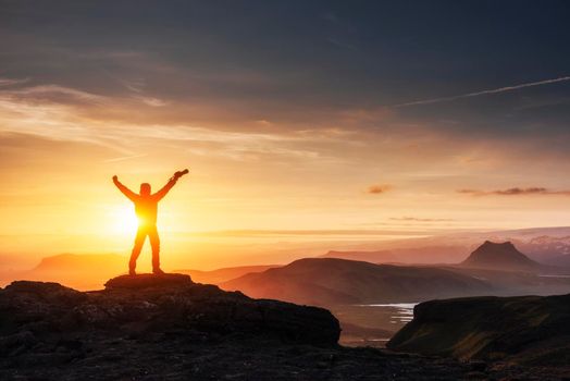 Happy man standing on a cliff at sunset.