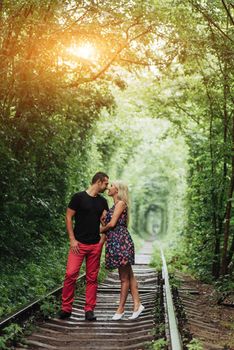 Loving couple in a tunnel of green trees on railroad.