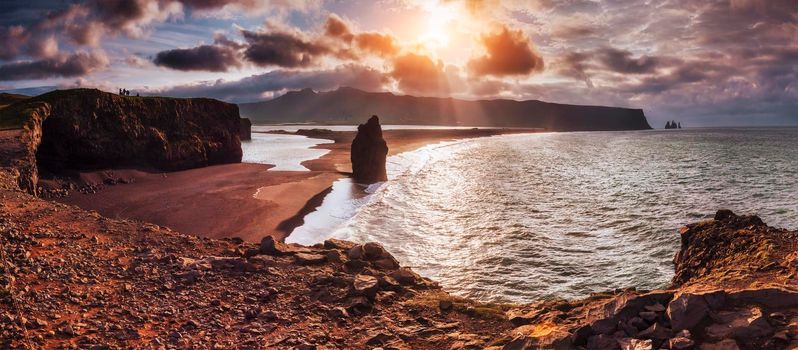 The black sand beach and mountains Reynisfjara Reynisfyal from Cape at sunset in Iceland.