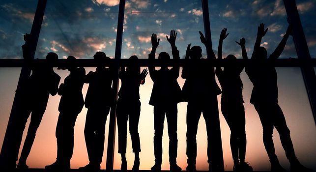 silhouette of a group of business people raising their hands .photo with copy space