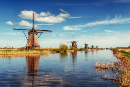 Colorful spring day with traditional Dutch windmills canal in Rotterdam. Wooden pier near the lake shore. Holland. Netherlands.