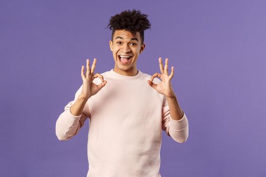 Portrait of satisfied young male student recommend online business school or education courses, give excellent feedback, show okay gesture as approve or like something really good.